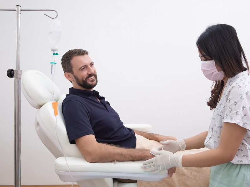A man sitting in a dental chair smiling at a dentist.
